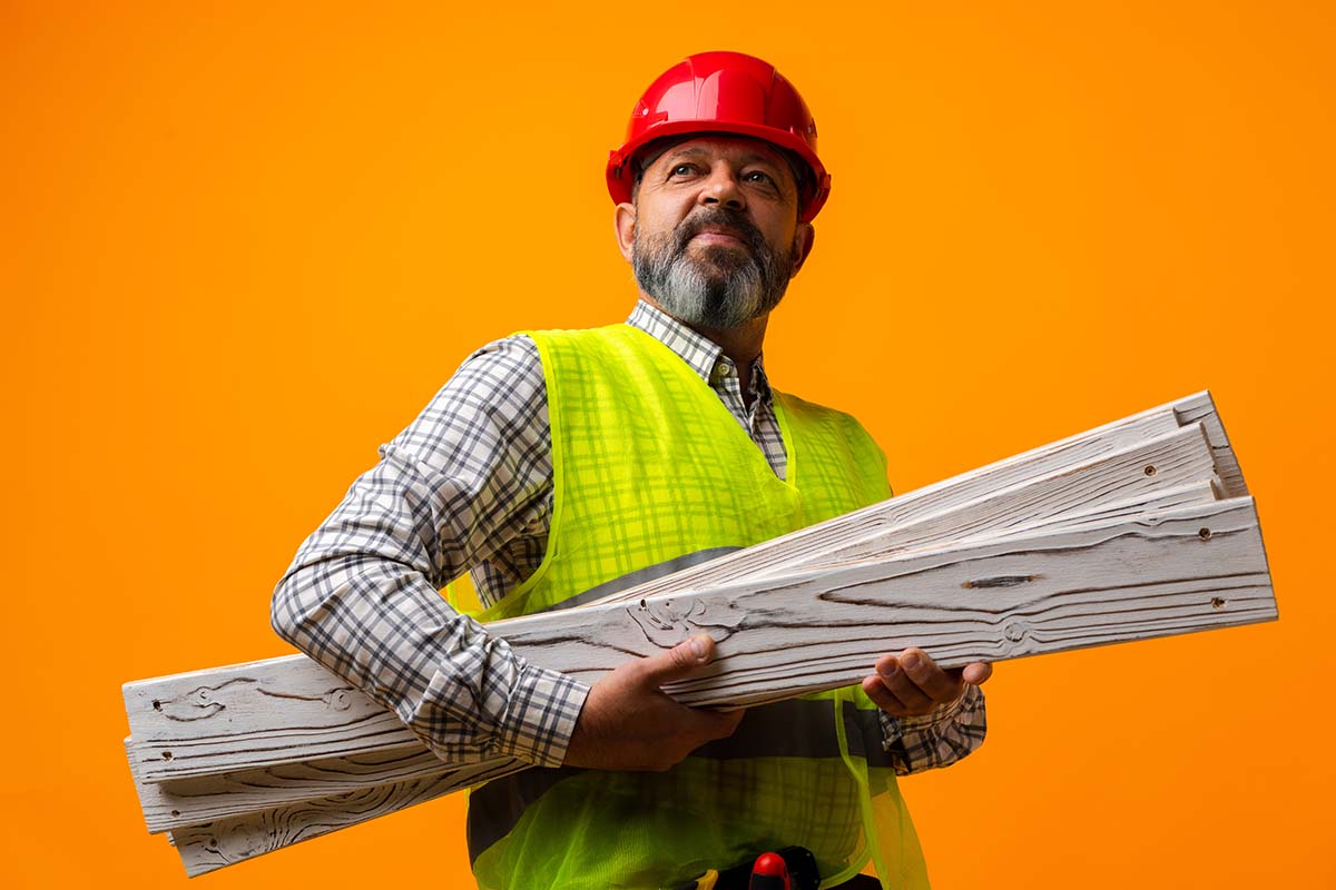 Builder Handyman With Wooden Planks Against Orange Background